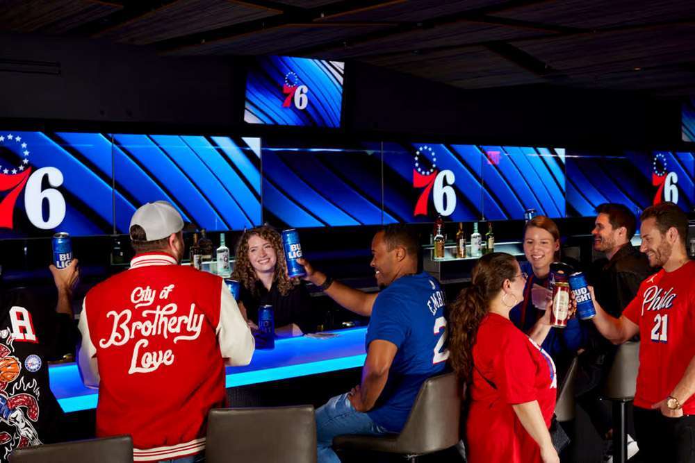 A group of Philadelphia 76ers fans celebrate with drinks at Wells Fargo Center, Philadelphia.