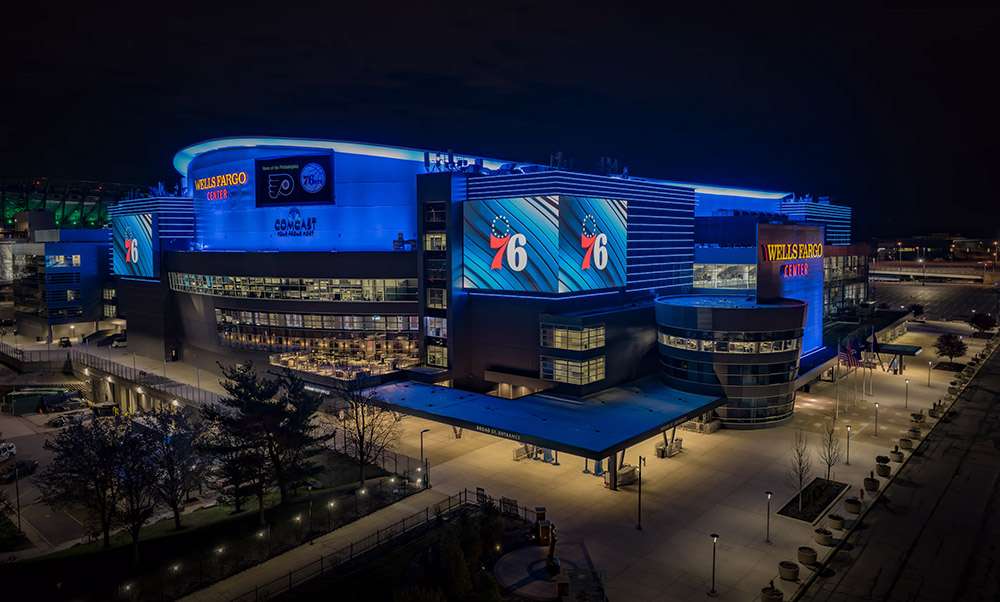 The Wells Fargo Center, Philadelphia, illuminated in 76ers colors at night.