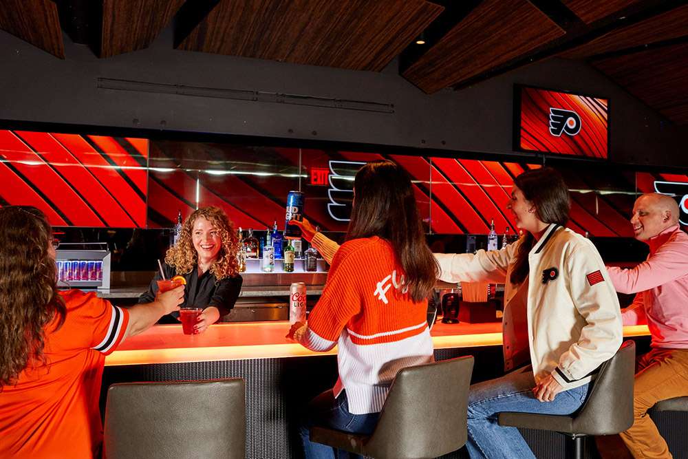 A group of Philadelphia Flyers fans raise their drinks to the bartender at Wells Fargo Center, Philadelphia.